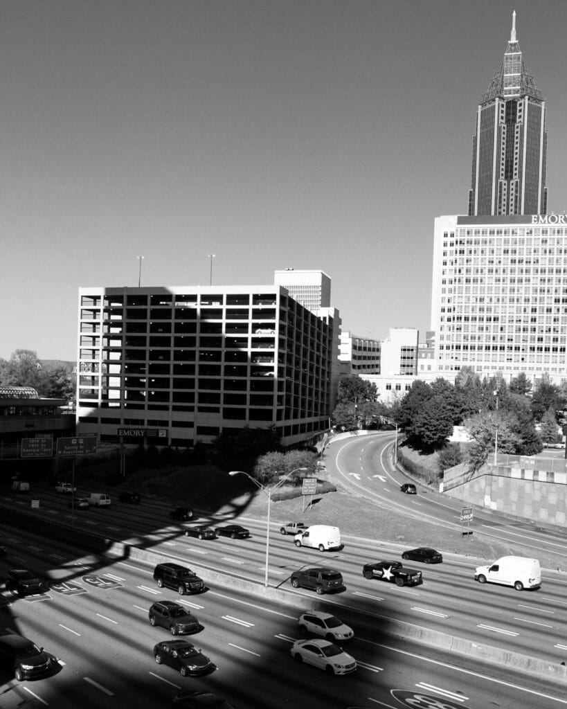 grayscale photo of cars on road near city buildings